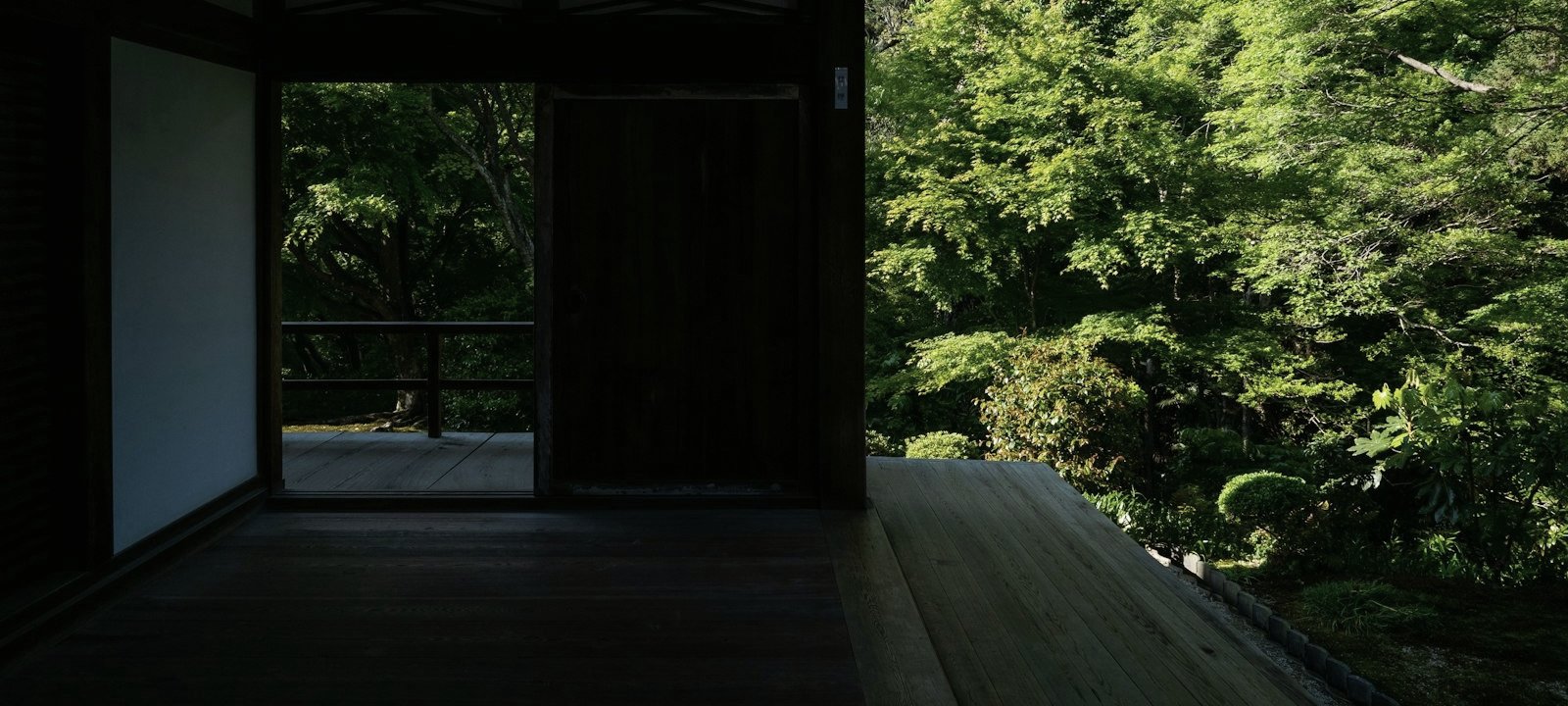 A shaded wooden veranda opening onto a bright green garden